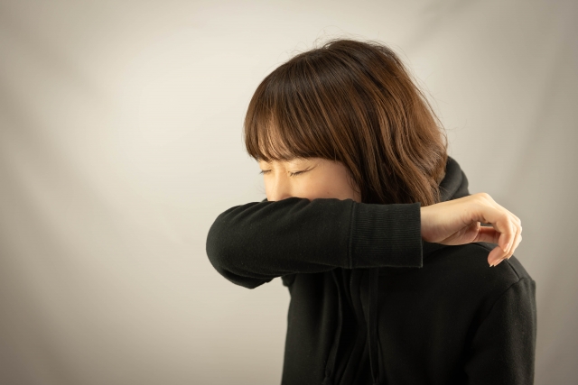 腕を曲げて口を覆って咳する画像
